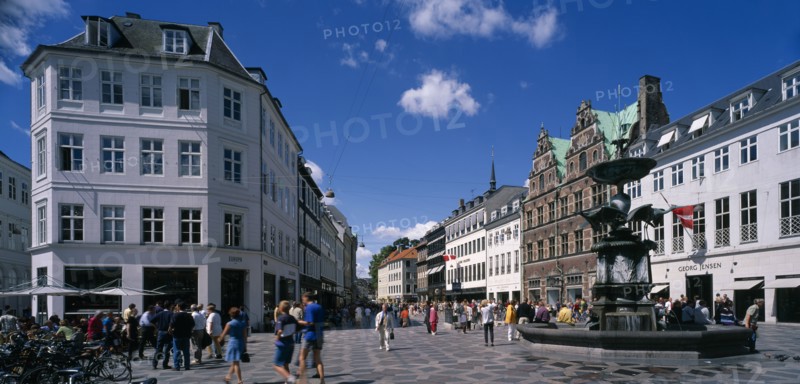 DENMARK, Zealand, Copenhagen , Stoget. People walking along street between traditional building near a fountain