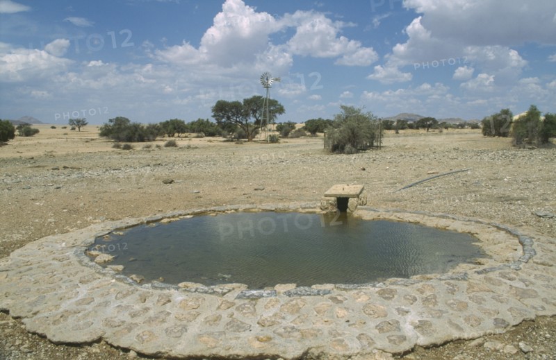 NAMIBIA, Namib Desert, Namib Naukluft Park, Animal waterhole with wind pump in the distance