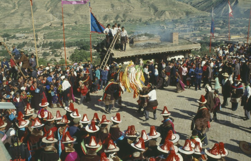 CHINA, Quinghai, Tongren, Tibetan festival with people wearing red tassled hats