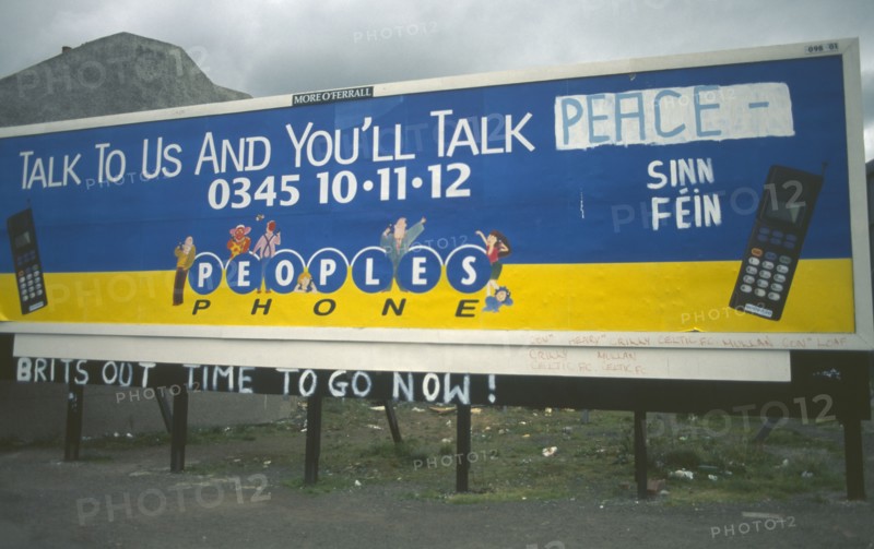IRELAND,  North , Belfast, "Peoples Phone billboard advertisment poster on Falls Road dawbed with Sinn Fein grafitti, Belfast"