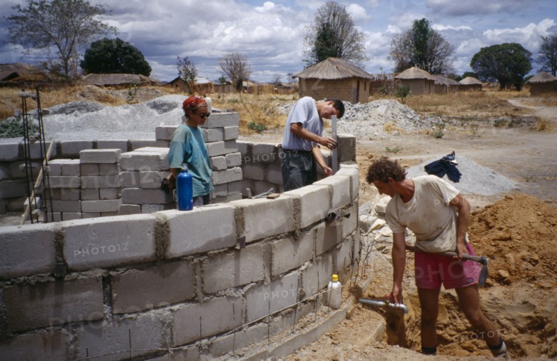 TANZANIA, Work, Men laying building blocks for a water tank in a small village with thatched huts