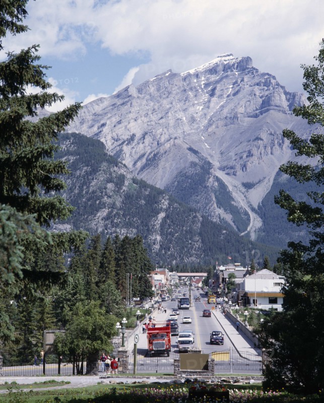 CANADA, Alberta, Banff, Banff Avenue the main straight street with a mountain peak behind seen between pine trees