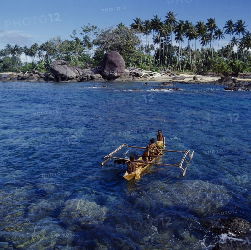 INDONESIA, Irian Jaya, Sorong, Children in outrigger canoe with beach behind