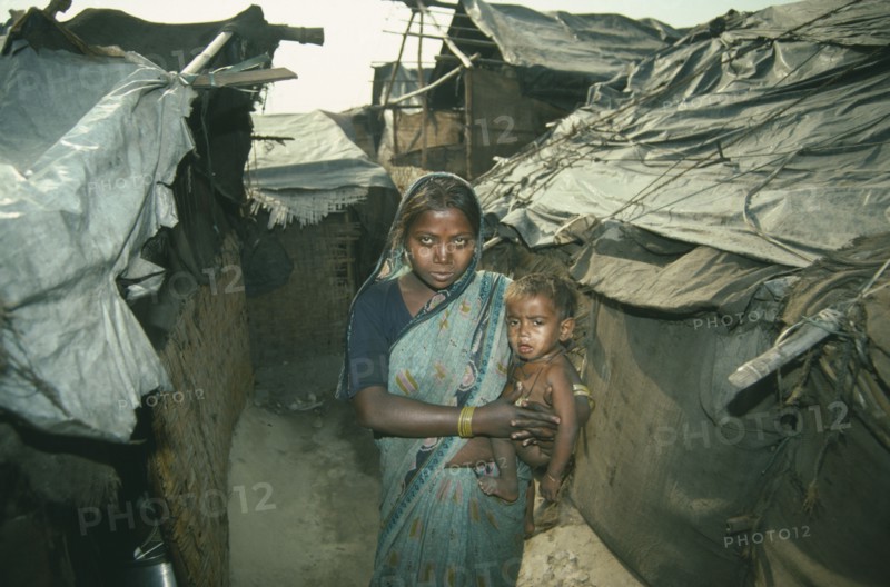 INDIA, Delhi, Woman holding small child in slum housing area