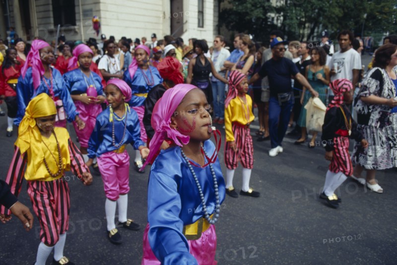 ENGLAND, London, Notting Hill Carnival. Children in costume blowing whistles during parade.