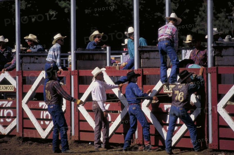 USA, South Dakota, Deadwood, Cowboys by the stalls of the Days Of 76 rodeo arena waiting to release a rider on a bull