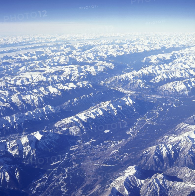USA, Montana, Glacier National Park, The snow covered Rocky Mountains with a thin layer of cloud seen from above