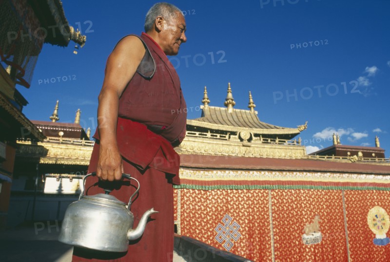 TIBET, Lhasa, Jokhang Temple, Monk carrying kettle on the roof of the temple