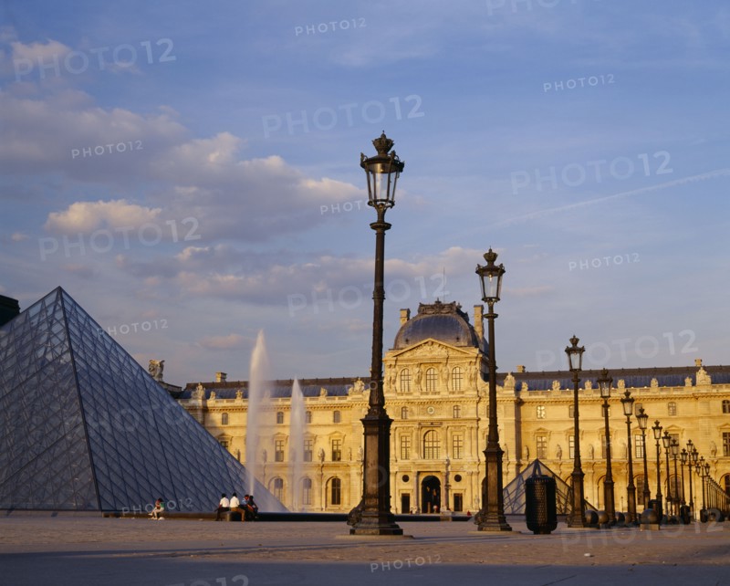 FRANCE, Ile de France, Paris, "Louvre,  Cour Napoleon and glass pyramid in evening light with decorative street lamps and fountain."