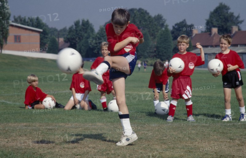 10001961 SPORT Ball Games Football Young boy kicking football during coaching derby.