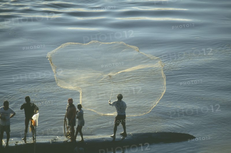 BRAZIL, Amazon, Rio Madeira River, Fishermen standing on long boat casting net