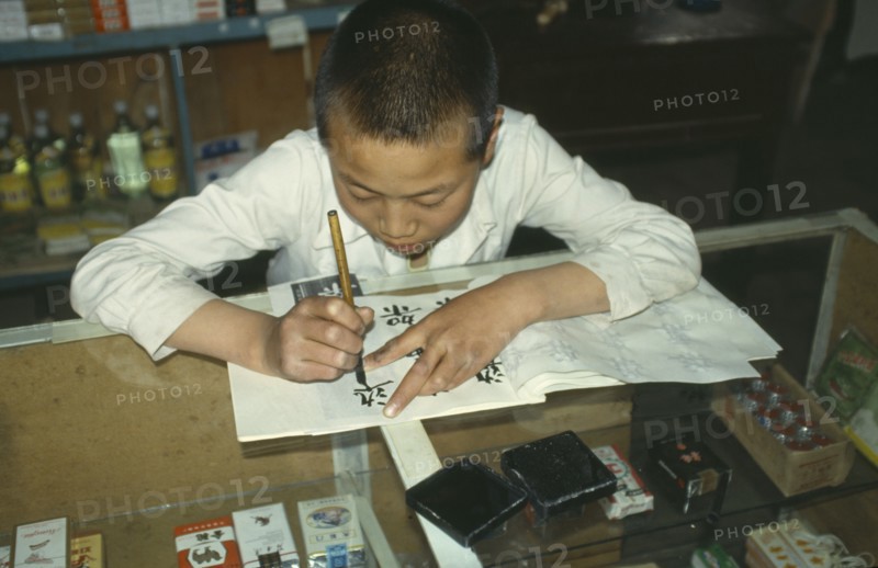 CHINA, Ningxia,  Boy Chinese writing at desk