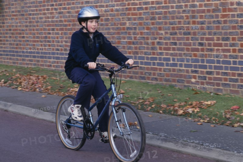 10125394 SPORT  Cycling  Child riding bicycle wearing safety helnet.