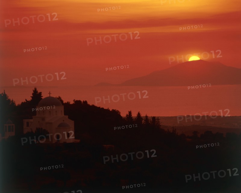 GREECE, Dodecanese Islands, Kos, "View past domed church in rural landscape to sun setting behind an island out at sea, view from Zia Taverna"