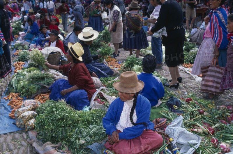 PERU, Cusco Department, Pisac, Vegetable stalls on the ground in cobbled a market place. Crowds of people.