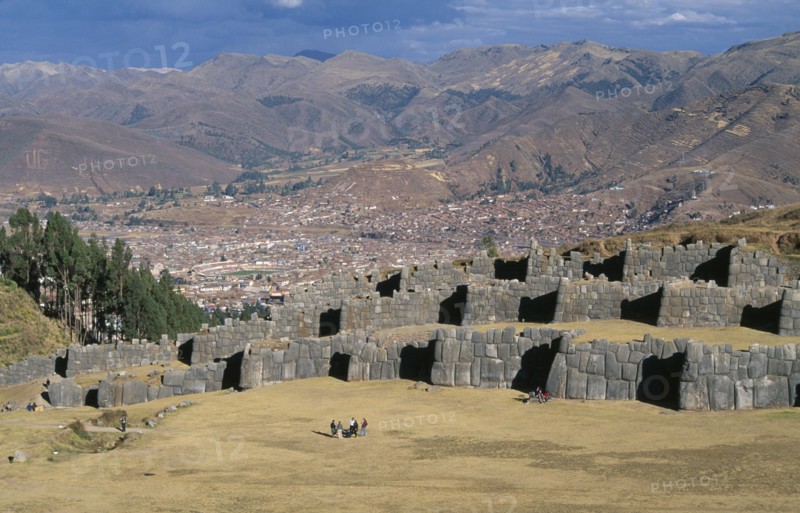 PERU, Cusco Department, Sacsayhuamán, Looking down on visitors walking between the Inca walls and Cusco in the distance.