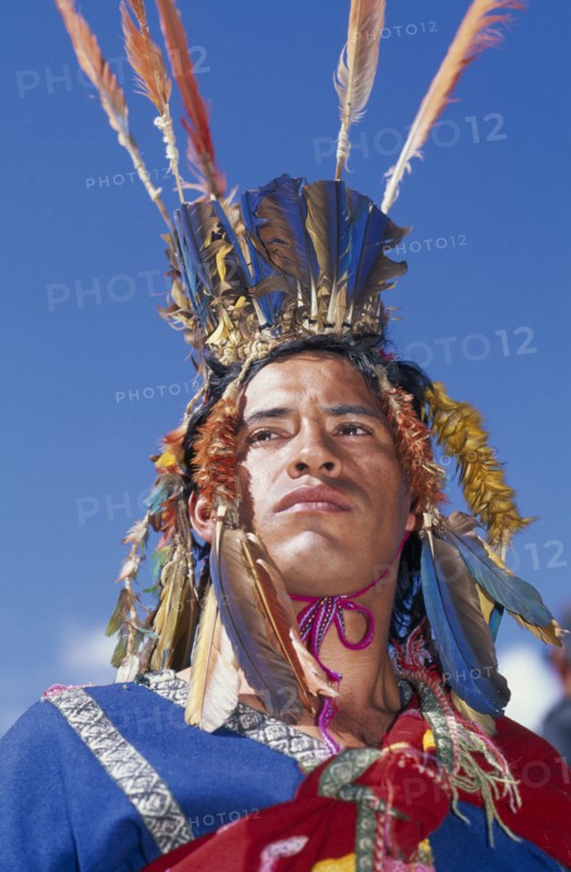 PERU, Cusco, Male figure in traditional costume and feathered headress at Inti Raymi.  Head and shoulders shot. Cuzco