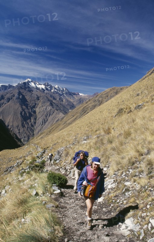 PERU, Cusco Department, The Inca Trail, Treckers with back packs walking up Dead Woman´s Pass.  View towards the mountains behind them.