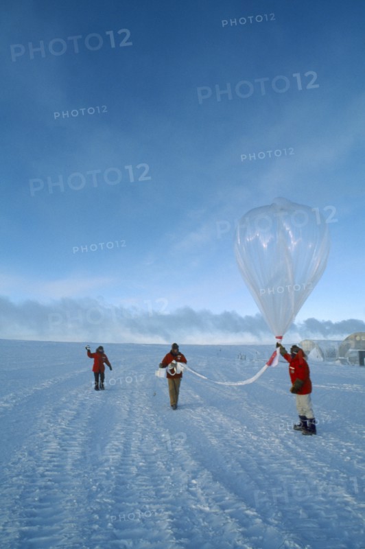 ANTARCTICA, South Pole, Three figures launching a balloon to measure amounts of ozone in the air at various altitudes.   US Amundsen-Scott South Pole Station.