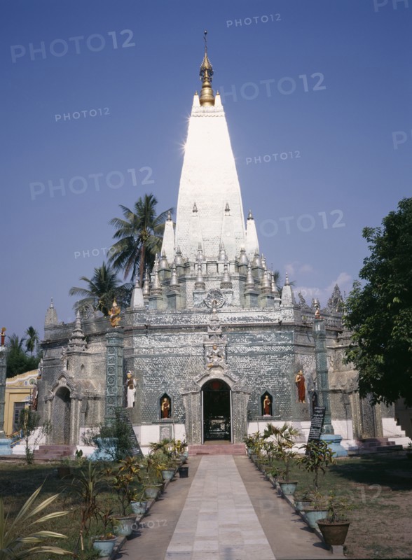 MYANMAR, Yangon, "Buddhist temple exterior with the sun reflecting off the silver spire, view along path towards the entrance. "