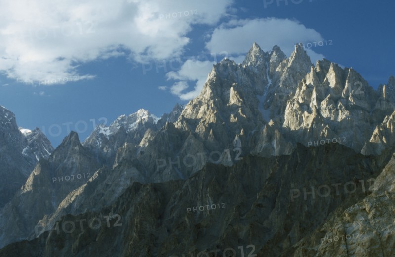 PAKISTAN, Hunza, Karakorum, Jagged peaks of the Karakorum mountain range on the Silk Route with white cloud drifting overhead.