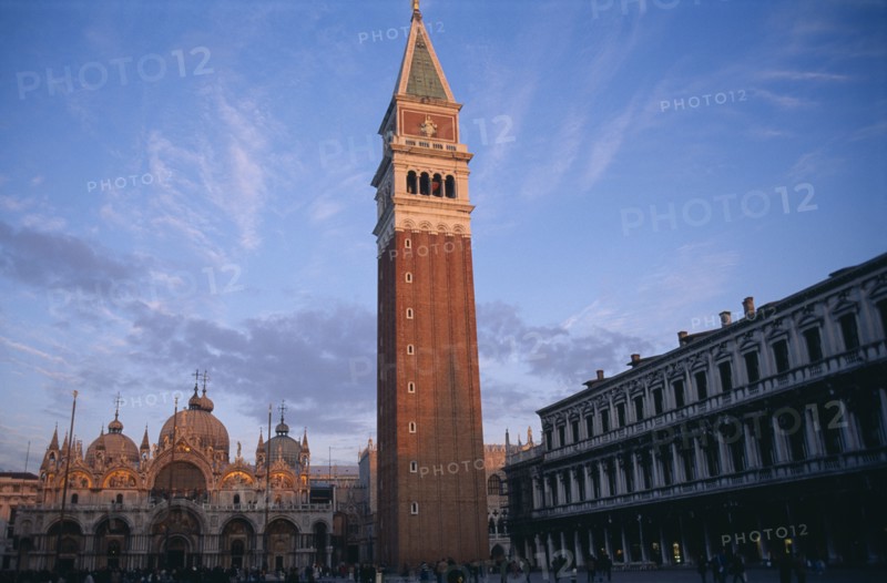 ITALY, Veneto, Venice, The Piazza San Marco with the Campanile bell tower in the foreground and the Basilica di San marco behind.  Crowds of people and pigeons.