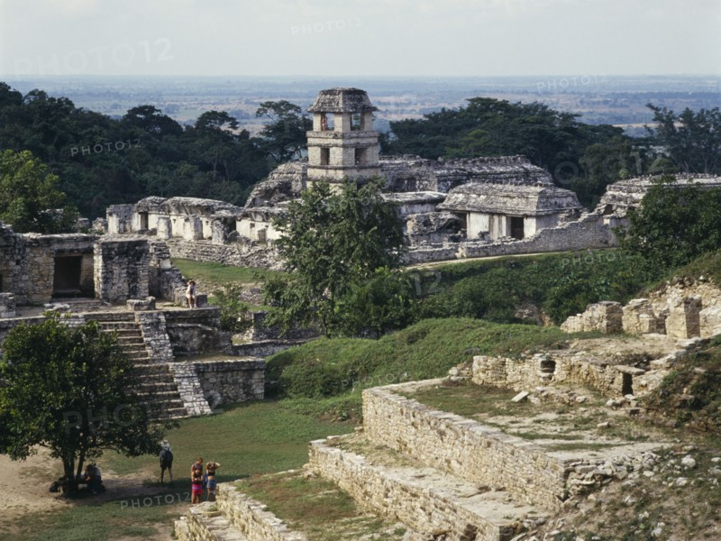 MEXICO, Chiapas State, Palenque, "View over ruins towards the tower of the Palace in Palenque ruins, visitors walking amongst the walls.  "