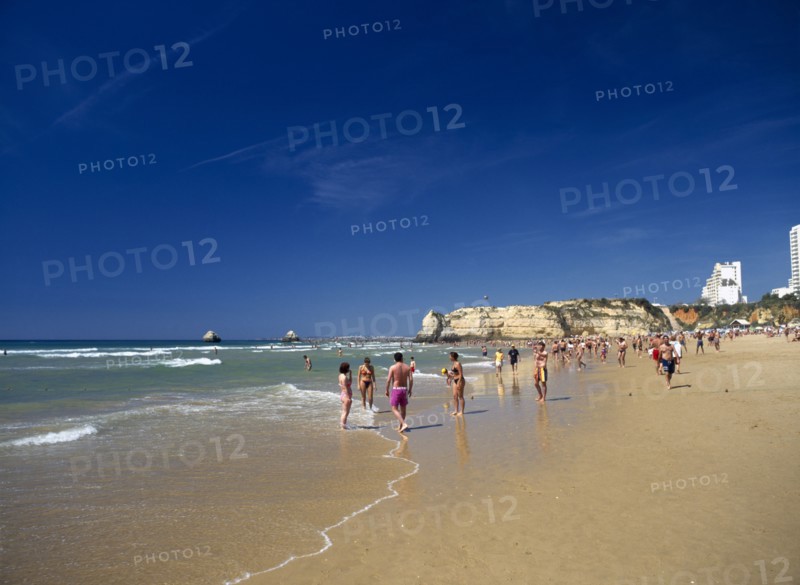PORTUGAL, Algarve, Praia da Rocha, View along beach with people walking along the waters edge