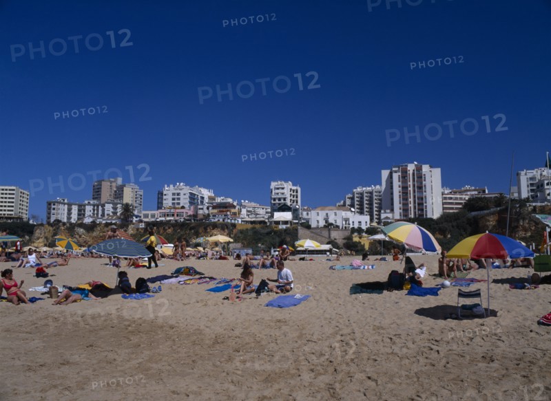 PORTUGAL, Algarve, Praia da Rocha, View of beach with people sunbathing and clifftop hotels behind
