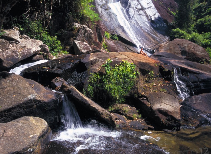 MALAYSIA, Kedah, Langkawi, Telaga Tujuh Seven Wells Waterfall with female tourist sitting on rocks