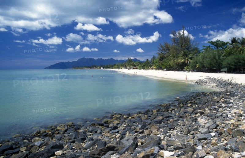 MALAYSIA, Langkawi, Kedah, Pantai Cenang beach looking towards Gunung Mat Cincang with a stoney beach in the foreground