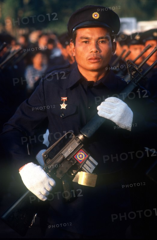 LAOS, Military, Electricity worker in militia uniform on parade carrying a USM M16 machine gun.