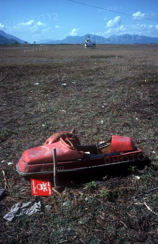 CAMBODIA, Work, Unexploded mine in a field on the Vietnamese border north west of Tinh Bien.  UN helicopter on the ground in the distance.