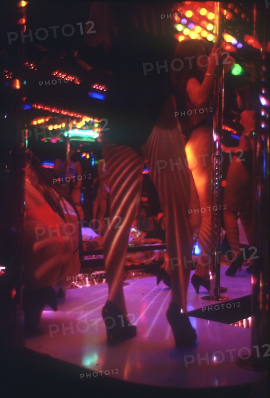 THAILAND, Bangkok, "Soi Cowboy Alley nightclub, view of stage and pole dancers, pink lighting. "