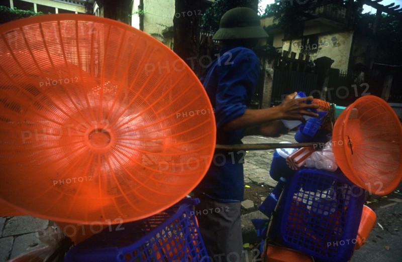 VIETNAM, Hanoi, Street vendor with display of coloured plastic baskets and utensils.