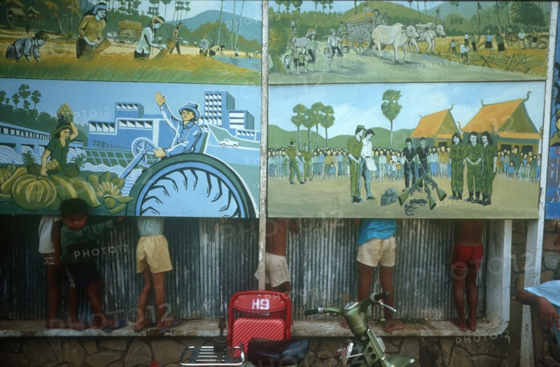 CAMBODIA, Phnom Pehn, Anti Khmer Rouge posters with line of children behind so only their legs can be seen.