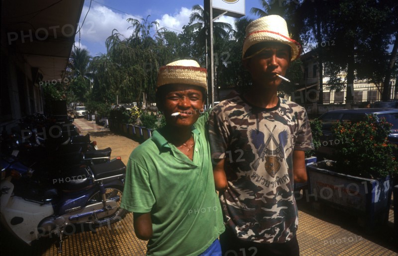 CAMBODIA, Phnom Pehn, Venteran amputees smoking cigarettes outside the Hotel Monorom.