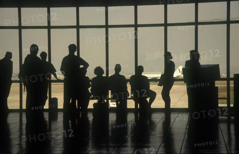VIETNAM, Hanoi, People at the airport terminal viewed from behind silhouetted against the window.