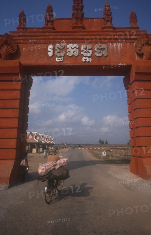 CAMBODIA, Moc Bai, Man on a bicycle crossing the border between Cambodia and Vietnam underneath large archway.
