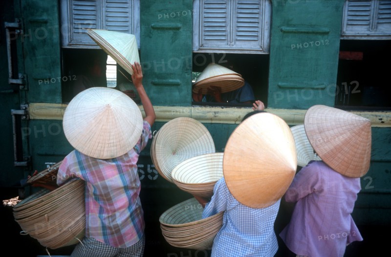 VIETNAM, Hue, "Traditional conical, straw hats being sold to train passengers at Hue station."