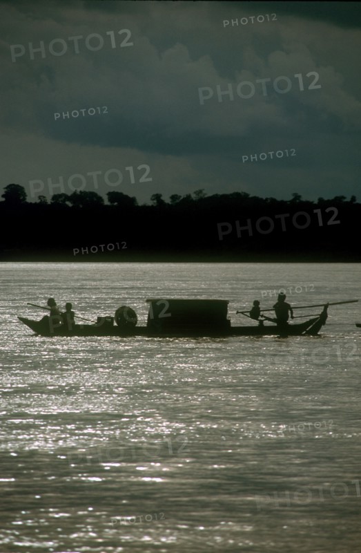 CAMBODIA, Stung Treng, "Narrow barge on the Mekong River, oarsmen silhouetted against sparkling water."