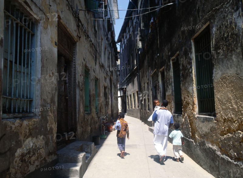 TANZANIA, Zanzibar Island, Zanzibar, "Stone Town.  Young man and three children walking along quiet, narrow street."