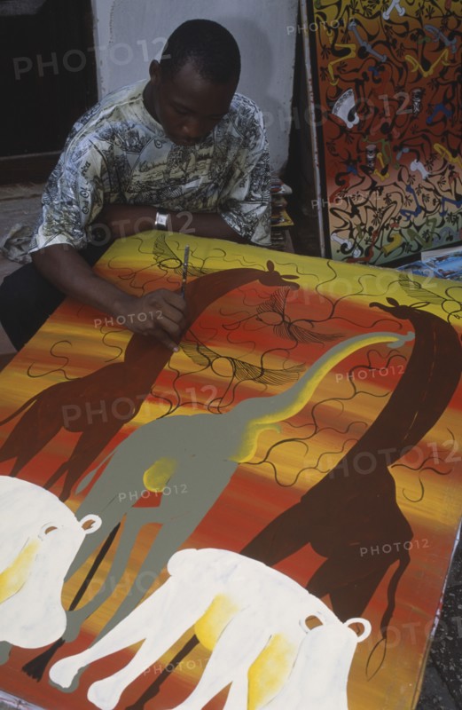 TANZANIA, Zanzibar Island, Arts and Crafts, Local artist working on painting in the Tingatinga style depicting African animals in bold colours.