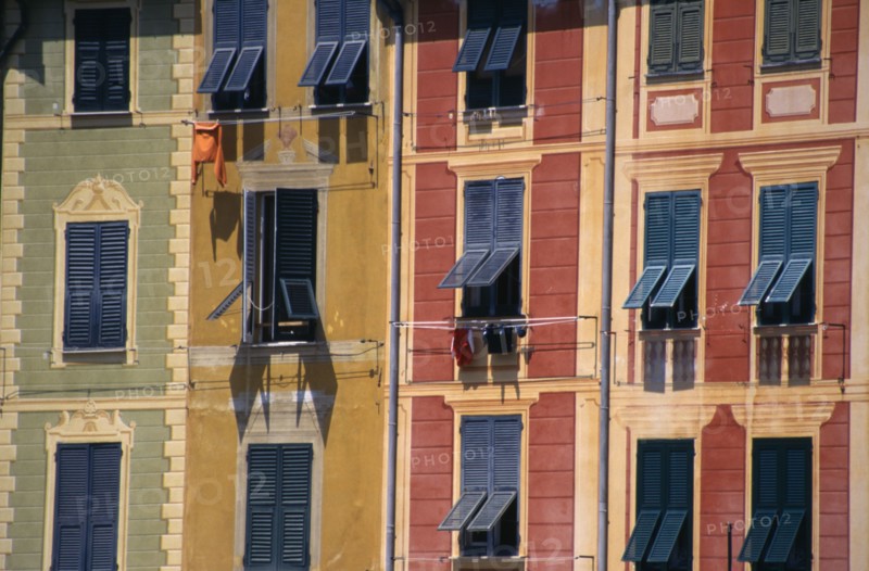 ITALY, Liguria, Portofino, Green yellow and red painted buildings with blue shutters by the harbour