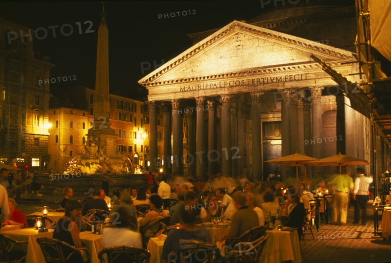 ITALY, Lazio, Rome, "The Pantheon, exterior view at night with people eating and drinking at outside tables in the foreground."