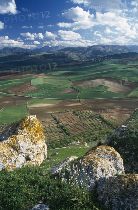 SPAIN, Andalucia, Malaga Province, "View over plain towards distant hills.  Large, lichen covered boulders in the foreground.  "
