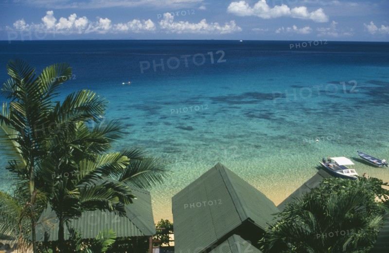 MALAYSIA, East Coast, Pulau Tioman Island, "Panuba Bay, north west coast.  View over palm trees and beach hut roof tops towards sea and horizon. "