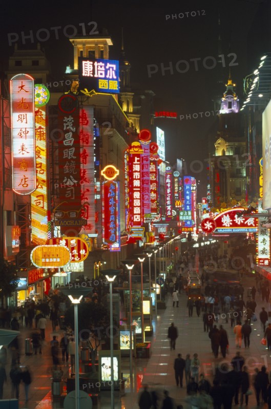CHINA, Shanghai, Busy pedestrianised street with neon signs and advertising hoardings illuminated at night.