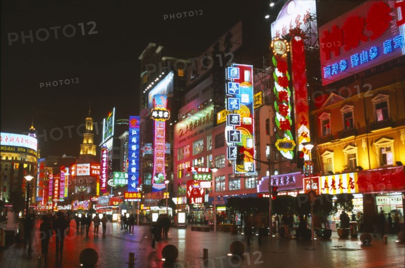 CHINA, Shanghai, Busy pedestrianised street with neon signs and advertising hoardings illuminated at night.