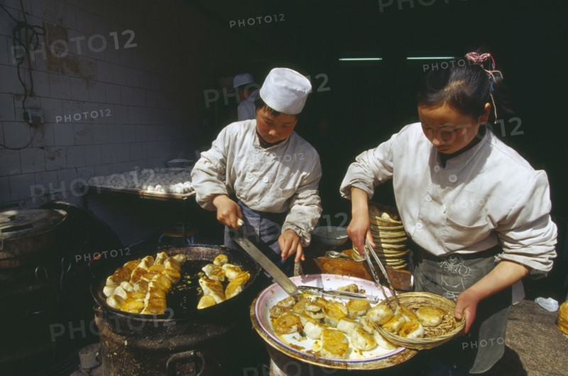 CHINA, Shaanxi Province, Xian, Two cooks preparing dish of fried food.
